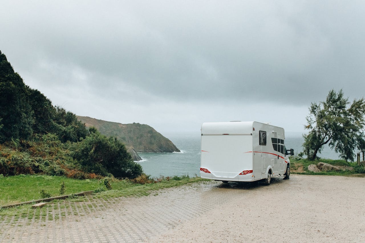 Services Serene coastal view with a caravan parked near the seaside under a cloudy sky.